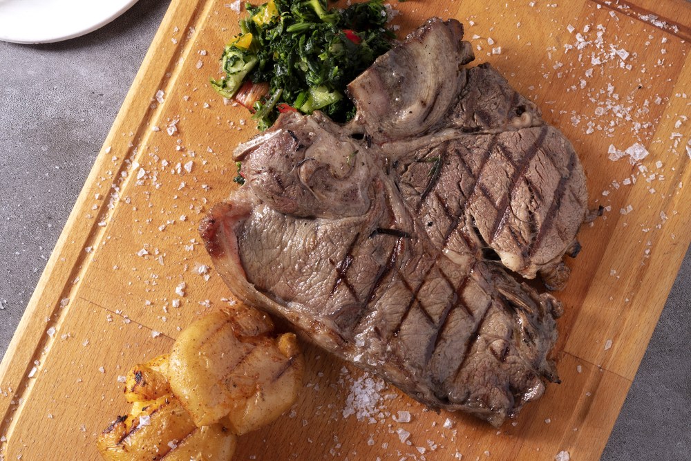 Deraliye Terrace - grilled veal chop on a wooden board with sauteed greens and baked potato